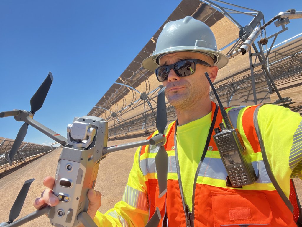 PAM owner-operator in safety equipment holding an enterprise drone at a solar facility.
