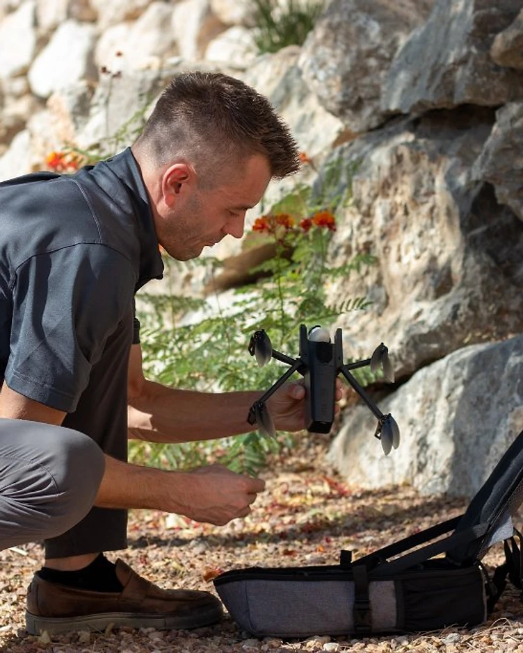 A remote pilot preparing a drone and field equipment before an outdoor operation.