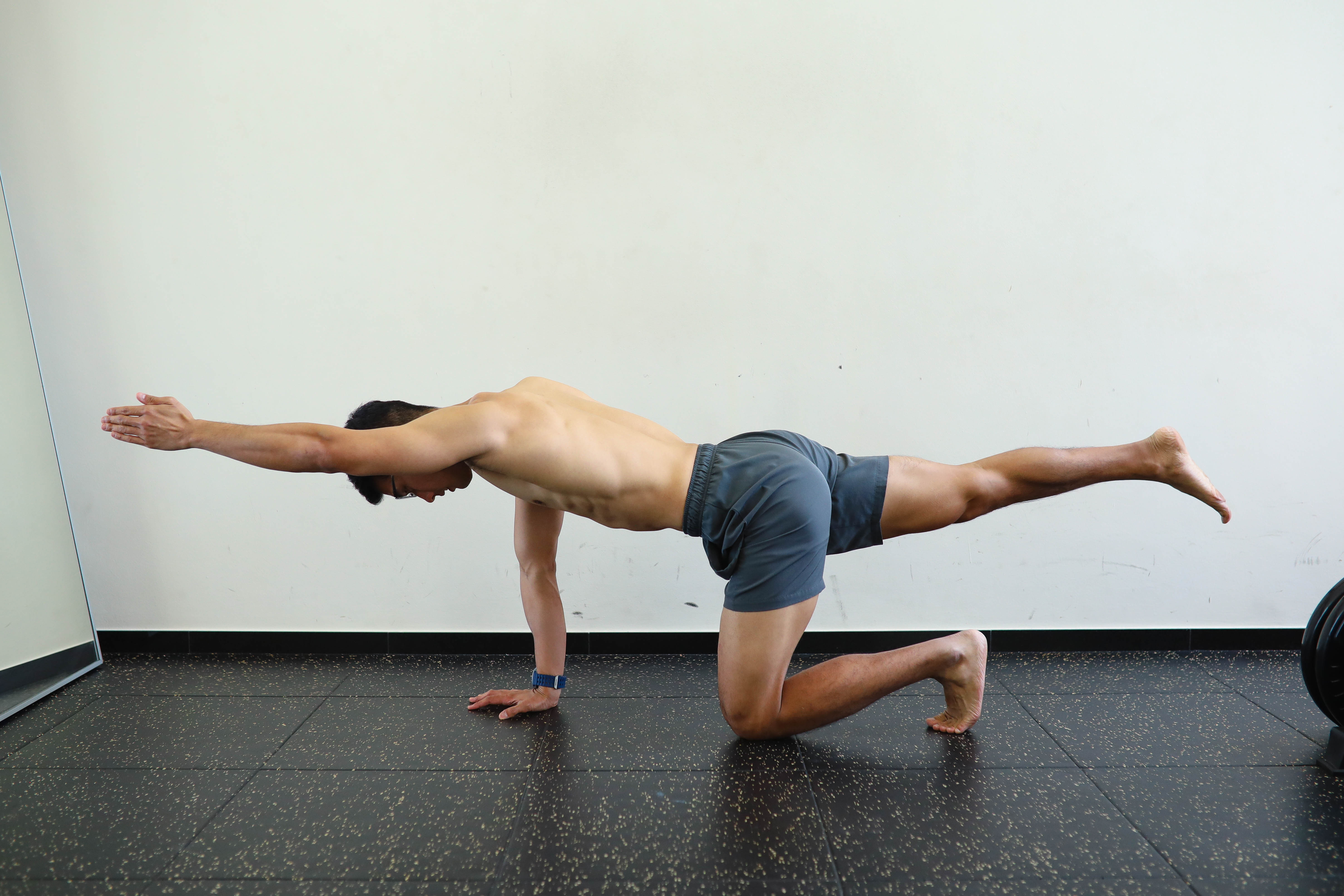 A client performing a controlled bird-dog core exercise on the studio floor