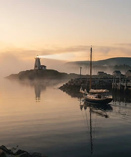 Segelboot verlässt bei Sonnenaufgang den Hafen – Symbol für die Jungfernfahrt