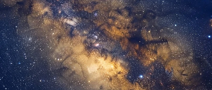 Dense star fields and golden nebula clouds toward the center of the Milky Way