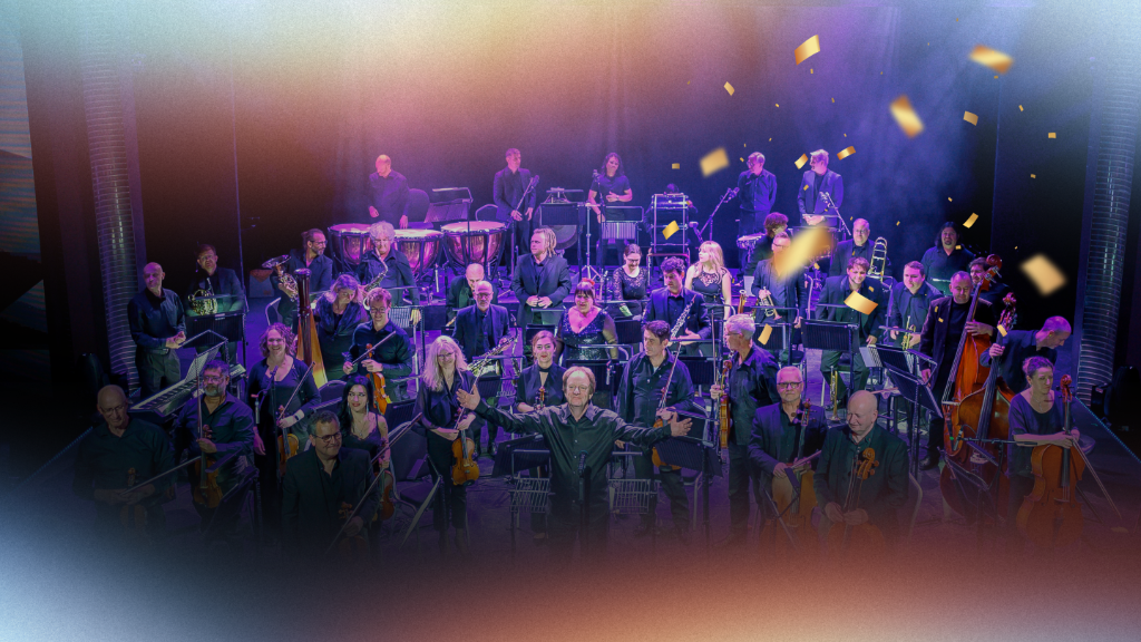 Live orchestra performing on stage with theatrical lighting