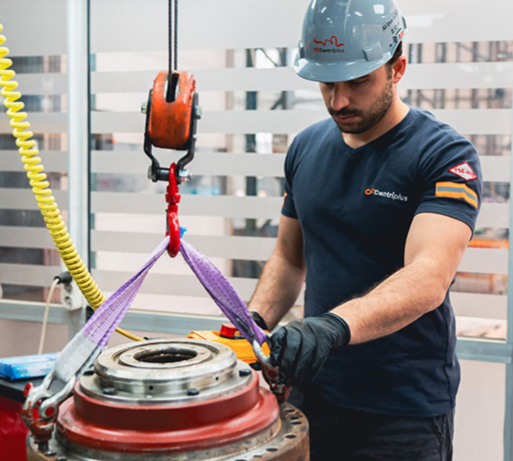 Field service engineer lifting a centrifuge component with a chain hoist