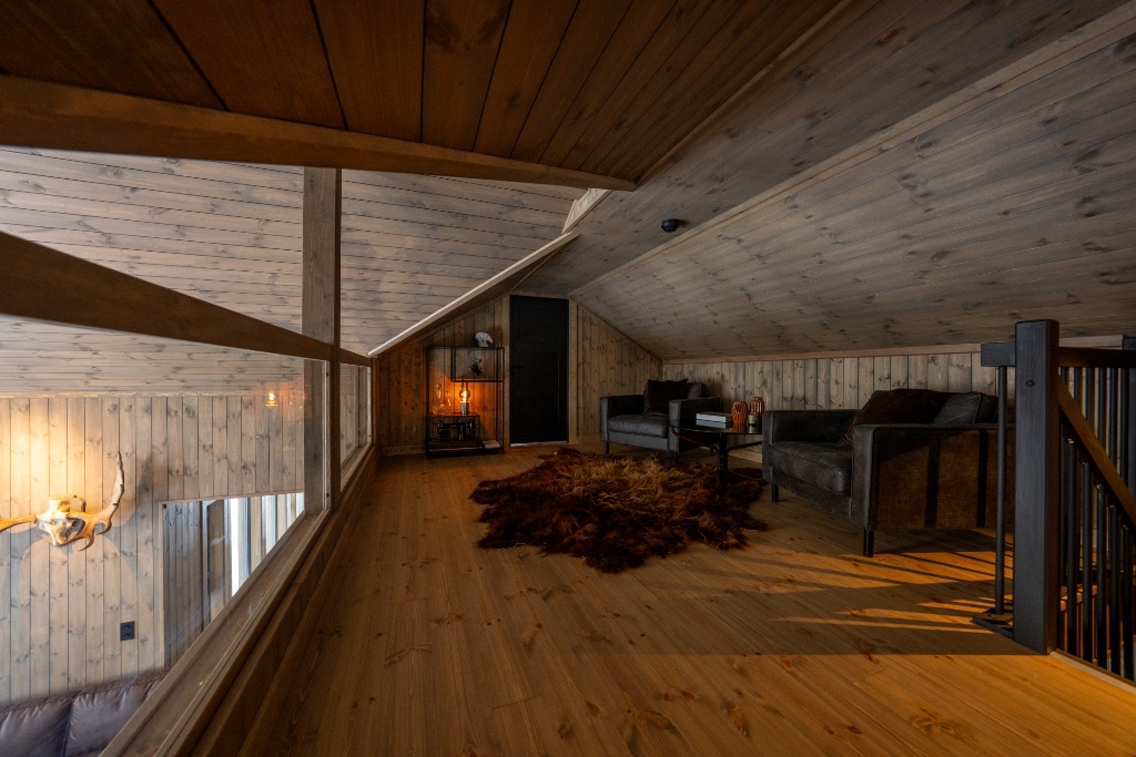 Loft lounge with sloped wood ceiling, leather armchairs and fur rug