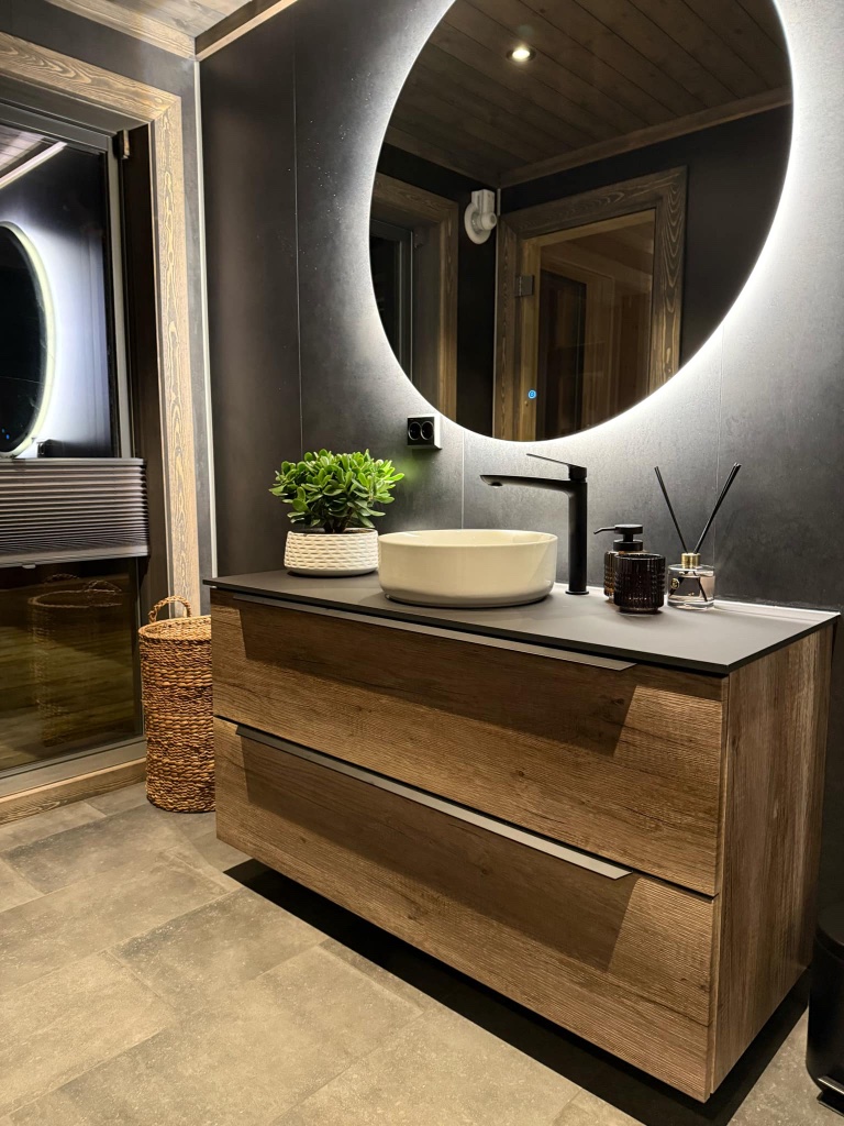 Modern bathroom vanity with backlit round mirror and matte-black fixtures