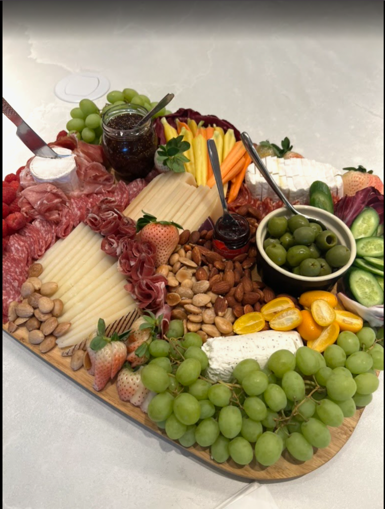 Composition — A composed charcuterie board — grapes, berries, cured meats, cheeses, olives and almonds.