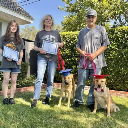 A Topline K9 family celebrating graduation with their two dogs.