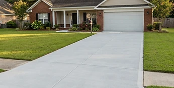 Completed residential concrete driveway with broom finish leading to a home