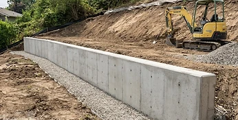 Completed poured concrete retaining wall on a graded residential property