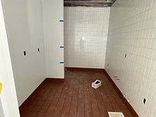 Restroom finish-out — tile floor and glazed wall tile; ceiling open for MEP.
