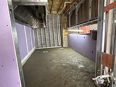 Kitchen rough-in — metal stud framing, exhaust hood, and plumbing rough-ins.