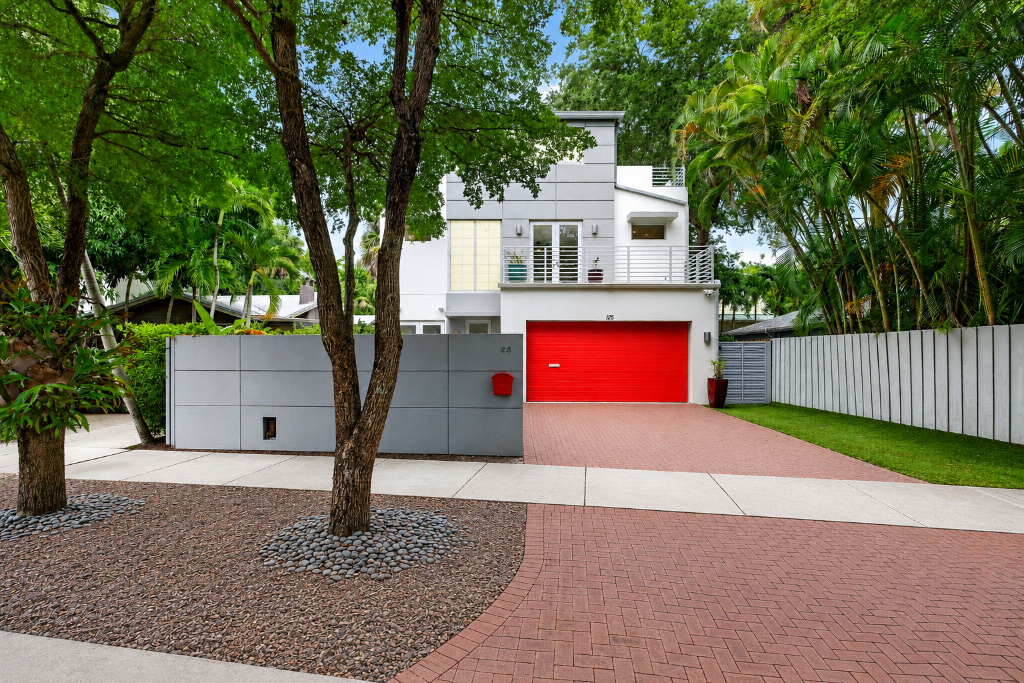 Contemporary three-story residence at 125 NE 16th Terrace in Victoria Park, Fort Lauderdale with a red garage door, brick driveway, and private pool