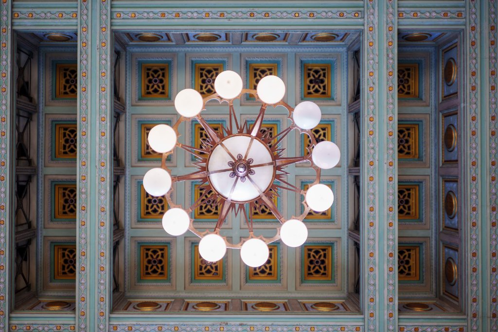 Ornate coffered ceiling with a central chandelier inside a historic Auckland building.