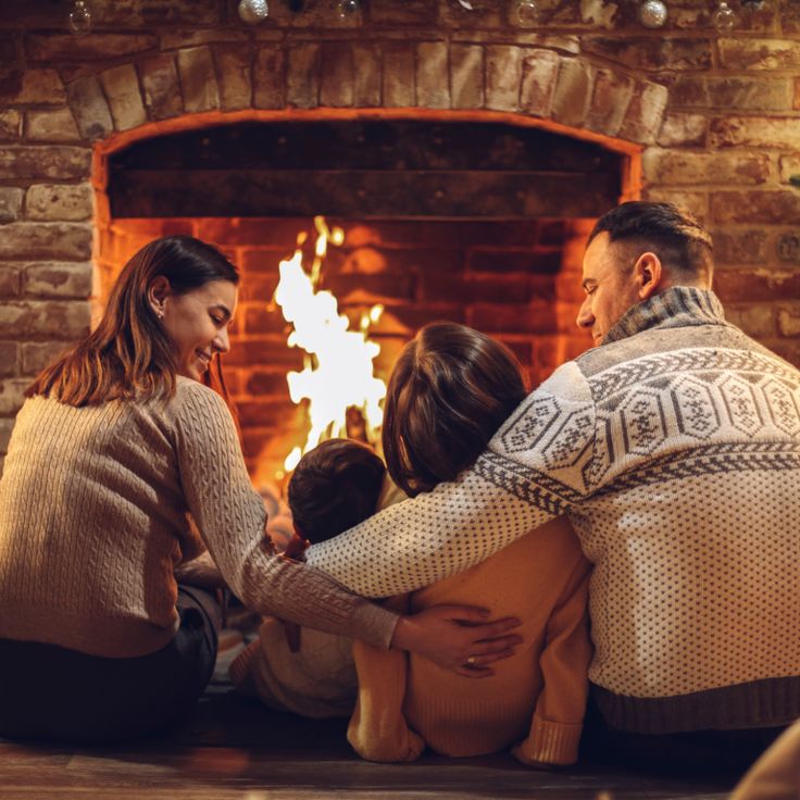 Family enjoying a warm fire in a brick fireplace — the comfort a safe, swept chimney protects