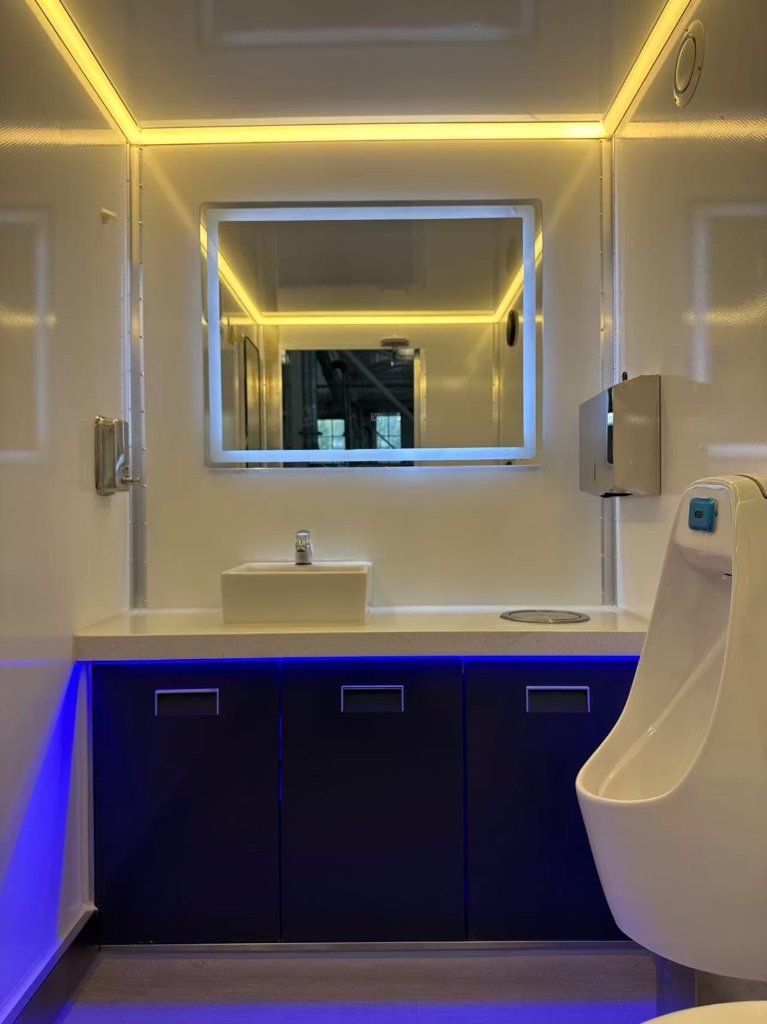 Symmetrical vanity with integrated LED lighting, built-in soap and paper-towel dispensers, and a flush urinal — engineered for comfort and cleanliness.