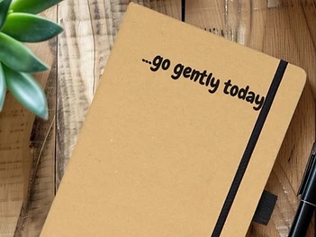 A Slow Daze journal and reflection sheets arranged on a wooden table