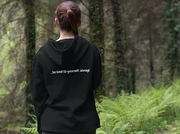 A person walking away along a woodland path, wearing a Slow Daze top