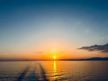 A calm sunset over still water with a golden reflection stretching toward the horizon
