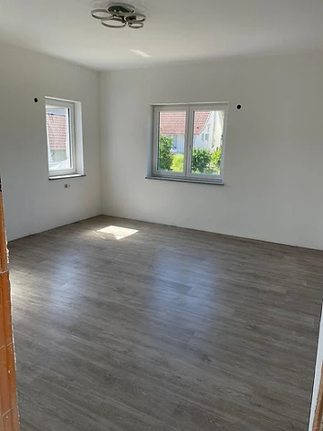 Frisch verputzter Raum mit neuen Fenstern und verlegtem Laminatboden