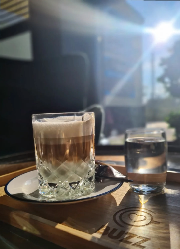 Geschichteter BUZZ-Kaffee auf Holztablett mit BUZZ Logo in der Cafe Lounge Wien