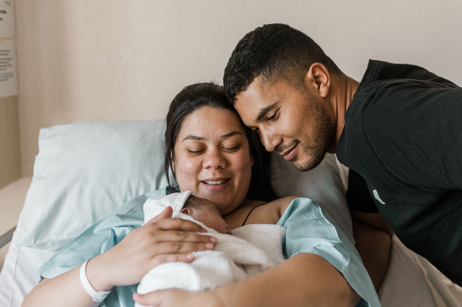 Smiling parents holding newborn baby after birth