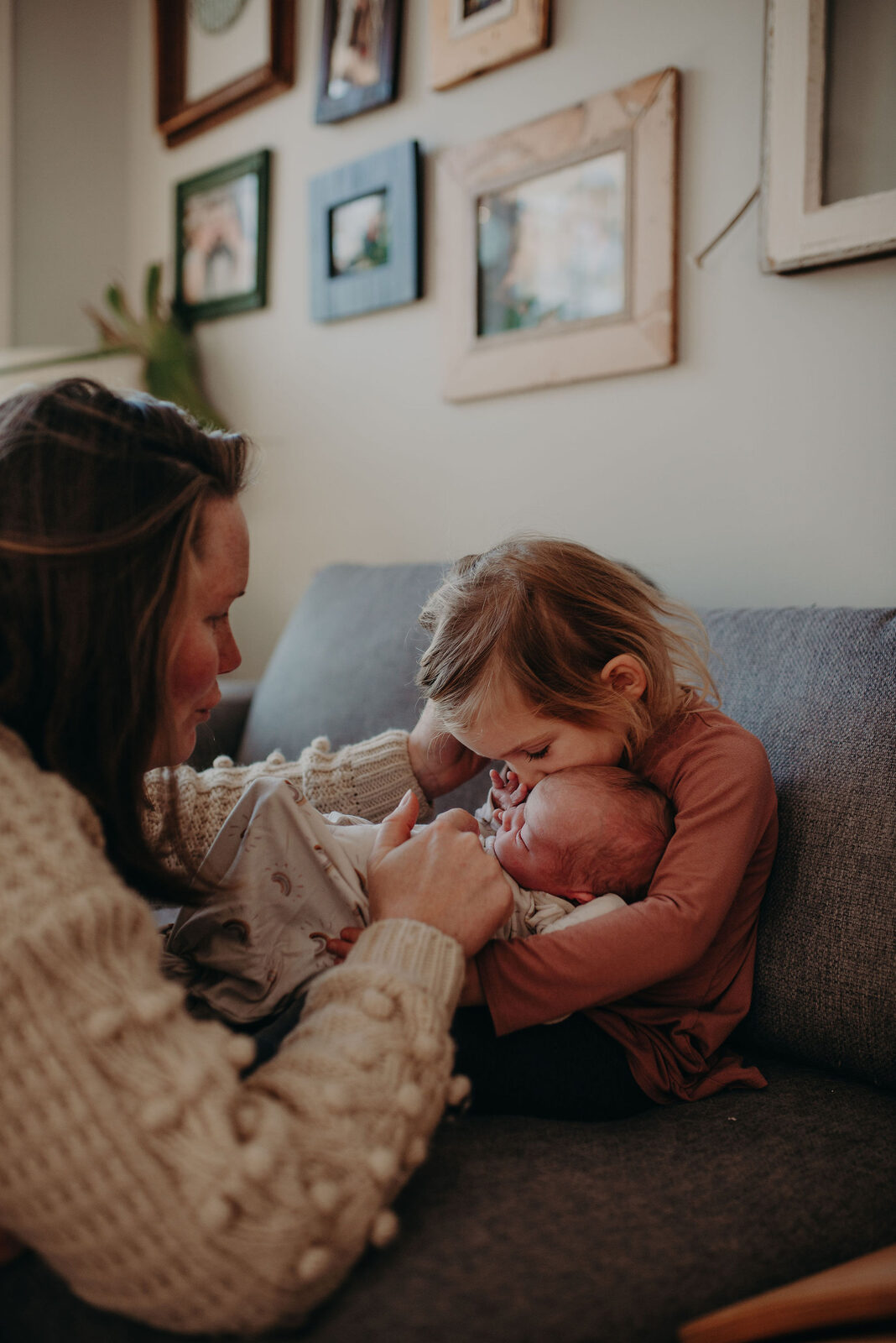 Mother and toddler bonding with newborn sibling at home