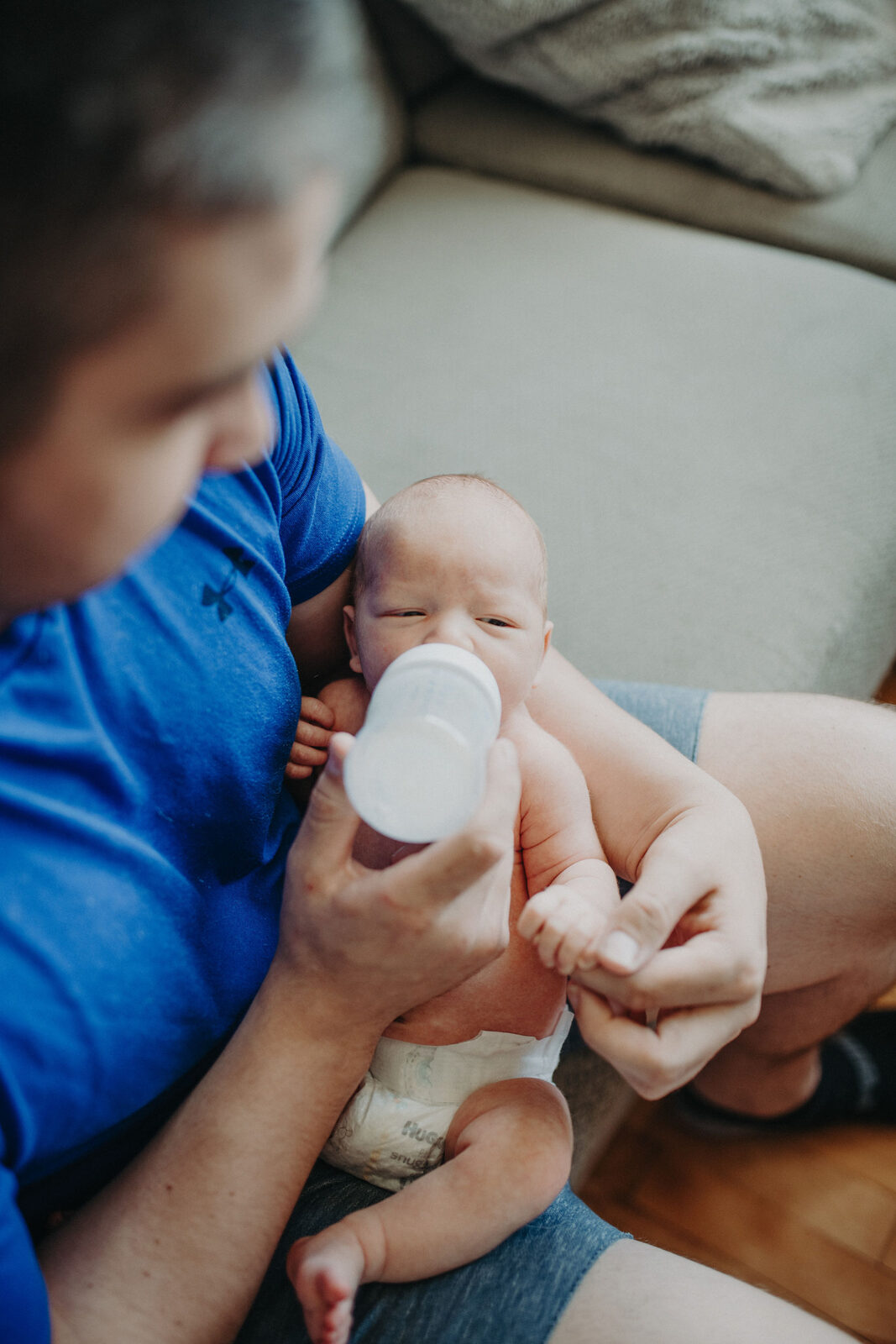 Father bottle-feeding newborn baby at home
