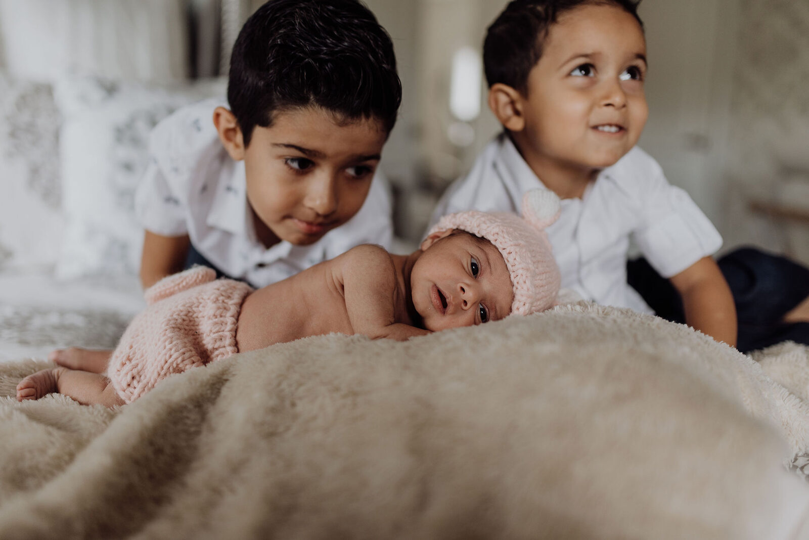 Two young brothers meeting their newborn baby sister