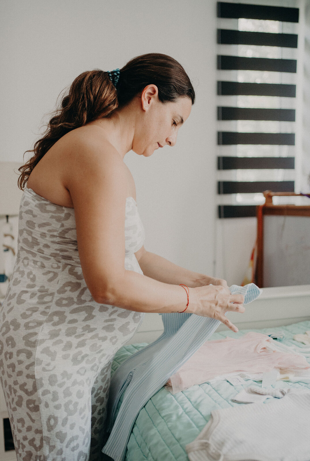 Pregnant woman preparing baby clothes at home in Temecula