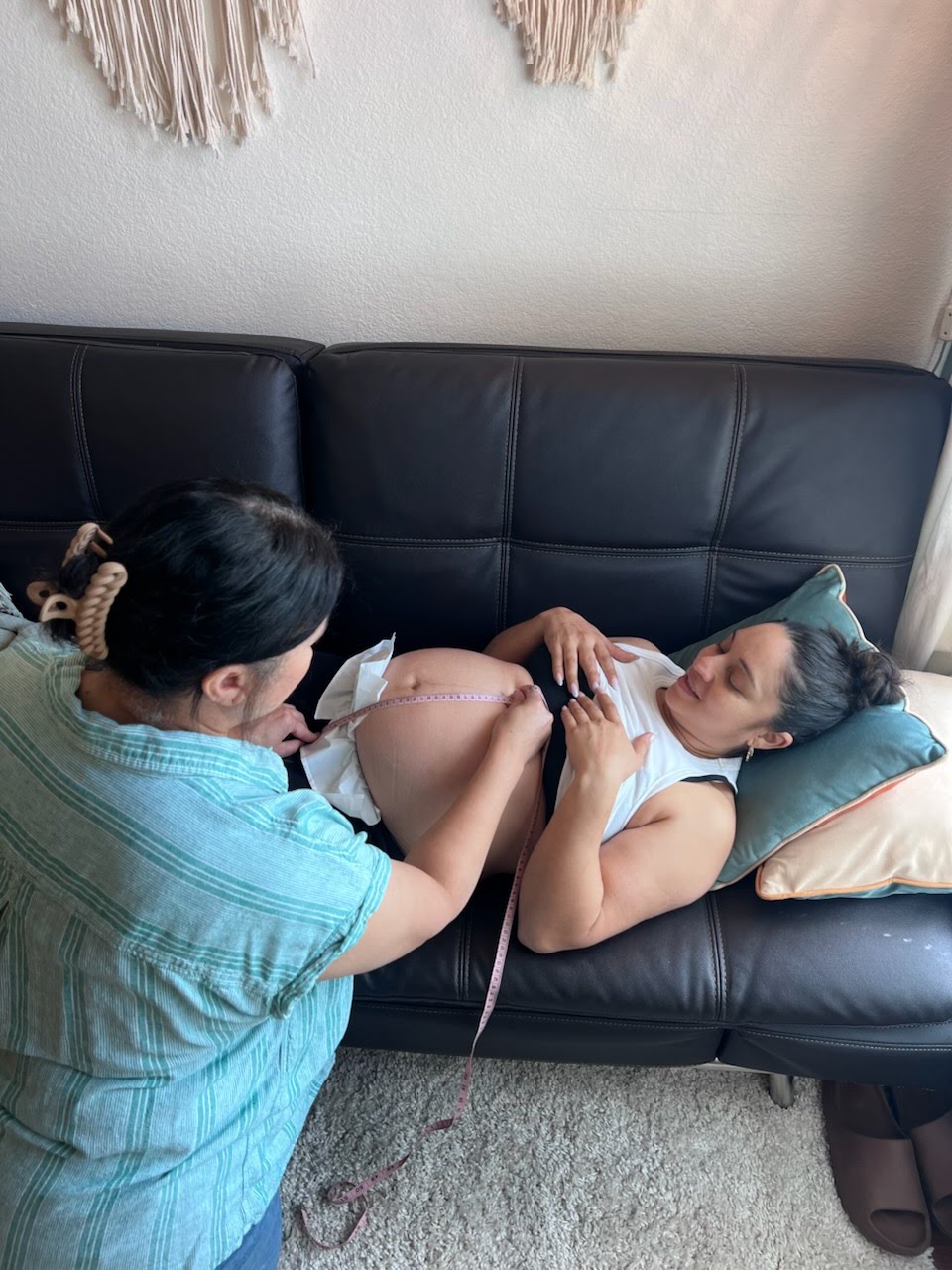 Tayna measuring a pregnant belly with a measuring tape during a prenatal visit