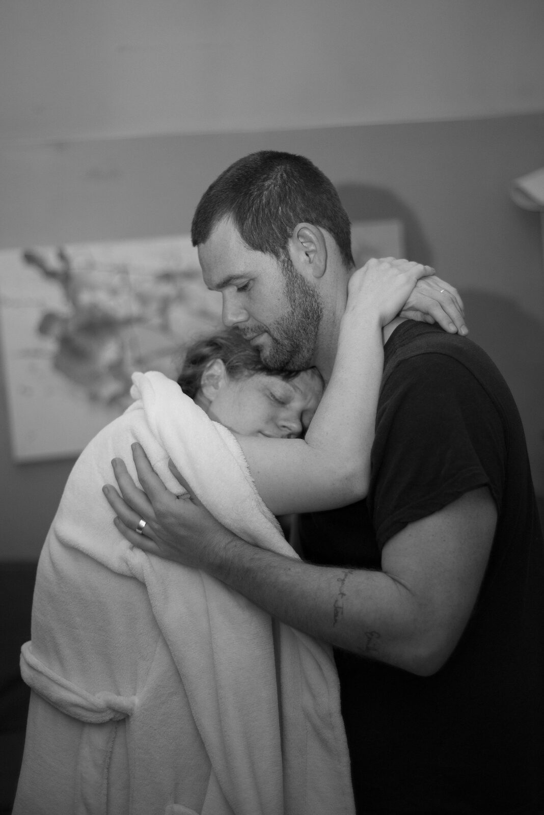 Black and white photo of partner embracing mother after birth