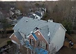 Tear-off in progress — old shingles removed and blue synthetic underlayment laid across the main roof slopes.