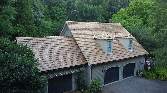 Finished roof — hand-split cedar shakes with copper valley flashing and skylight integration.