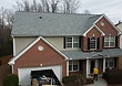 Near completion — final courses of shingles being laid and the job site cleared.