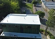 TPO membrane installation in progress, with ZIP System sheathing exposed and equipment staged on the lower roof.