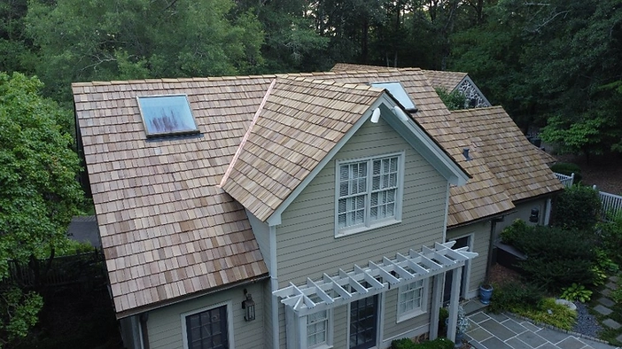 Finished roof — cedar shake with custom dormers, skylights, and copper flashing.