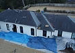 Tear-off underway — the 3-tab shingles stripped away, exposing clean roof decking along the side slope.