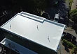Completed white TPO roof membrane with flashing and roof vents installed.
