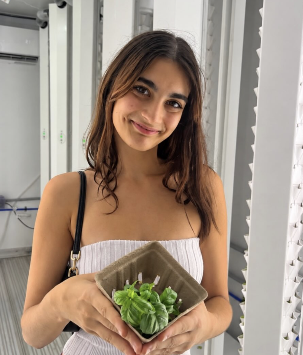 Student holding a basket of fresh basil in the growing corridor