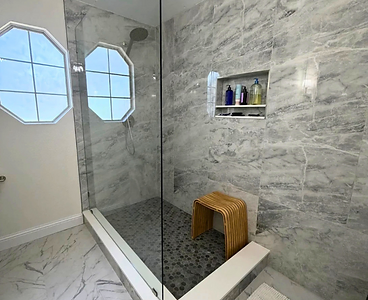 Walk-in shower with marble tile and frameless glass