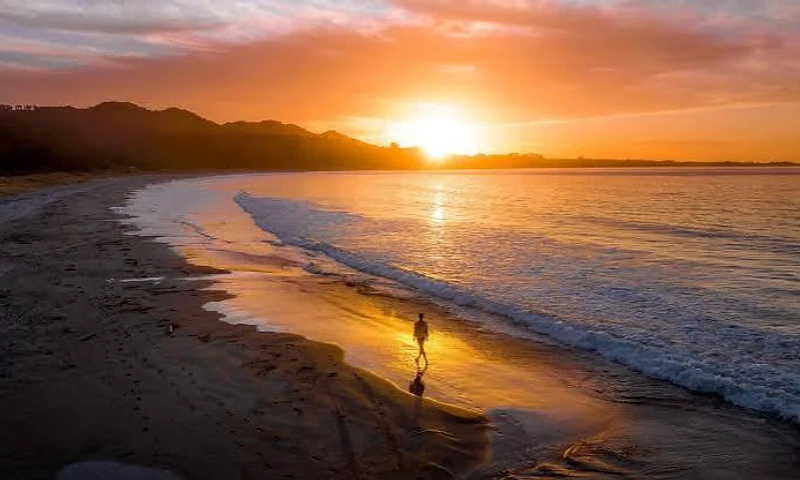 A woman standing still at sunset by the water