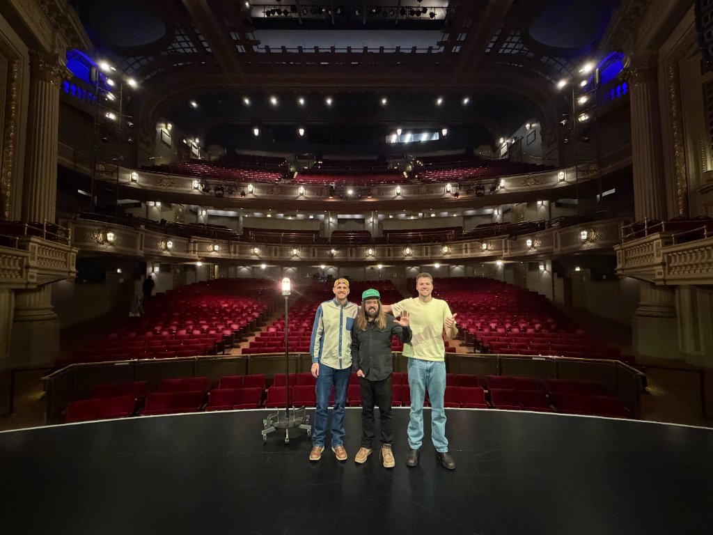 Scott Bedgood and fellow comedians waving on a grand theater stage