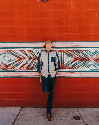 Scott Bedgood full body leaning against red painted mural wall