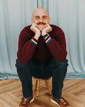 Scott Bedgood seated on a stool resting his chin on his hands