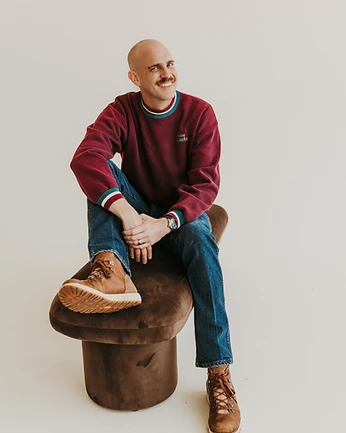 Scott Bedgood smiling while seated on velvet ottoman