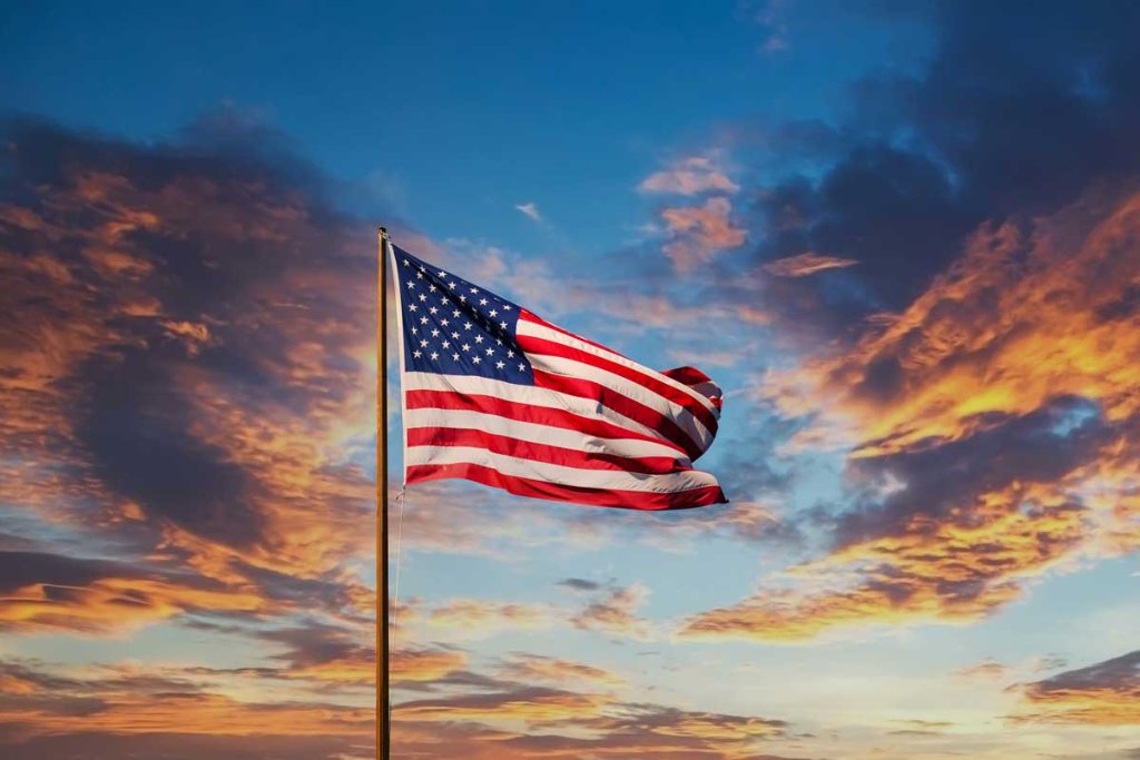 American flag waving at sunset — United Finishing Systems builds and manufactures in the USA