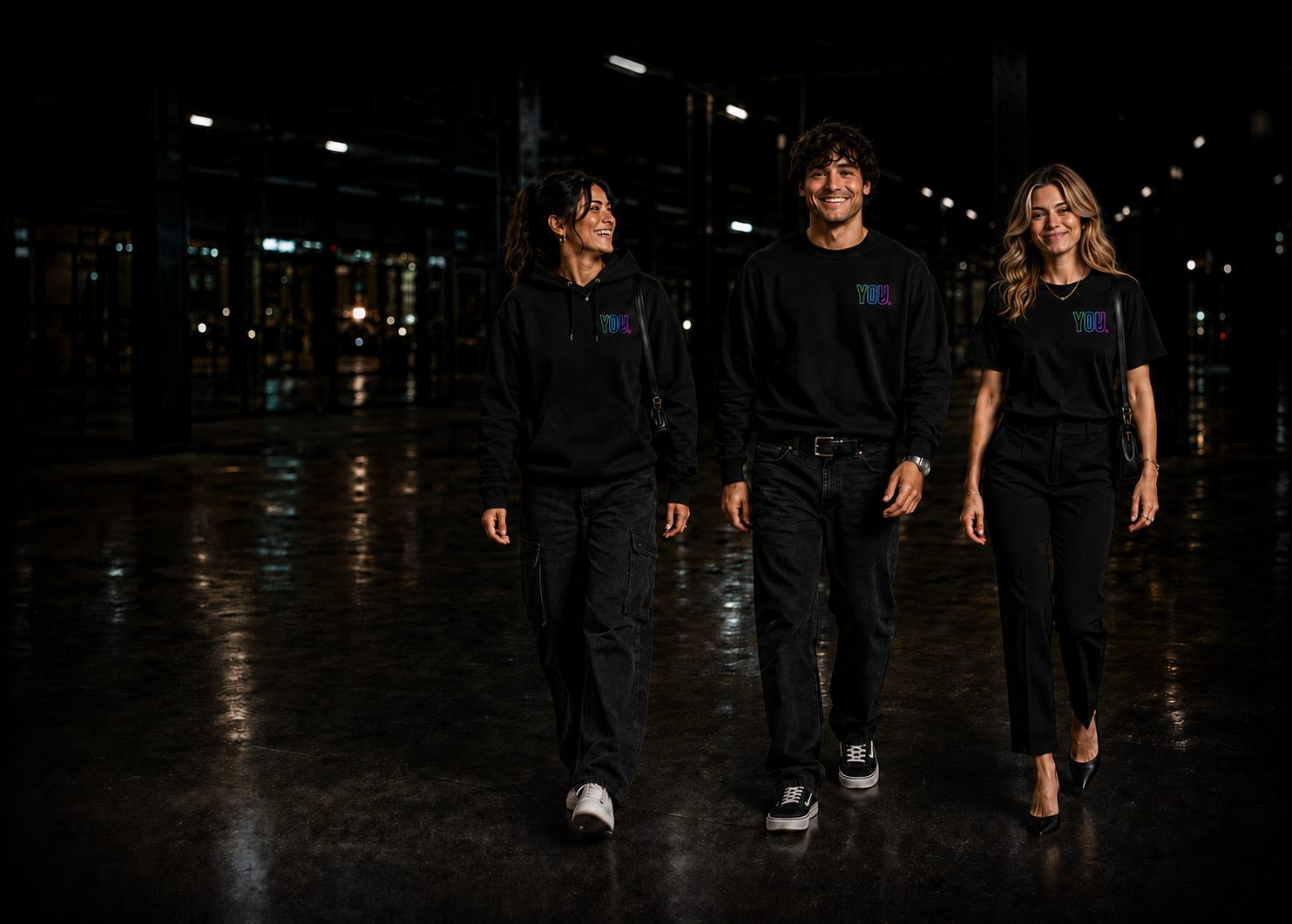 Three people wearing black YOU.project gear walking through a dark industrial hall