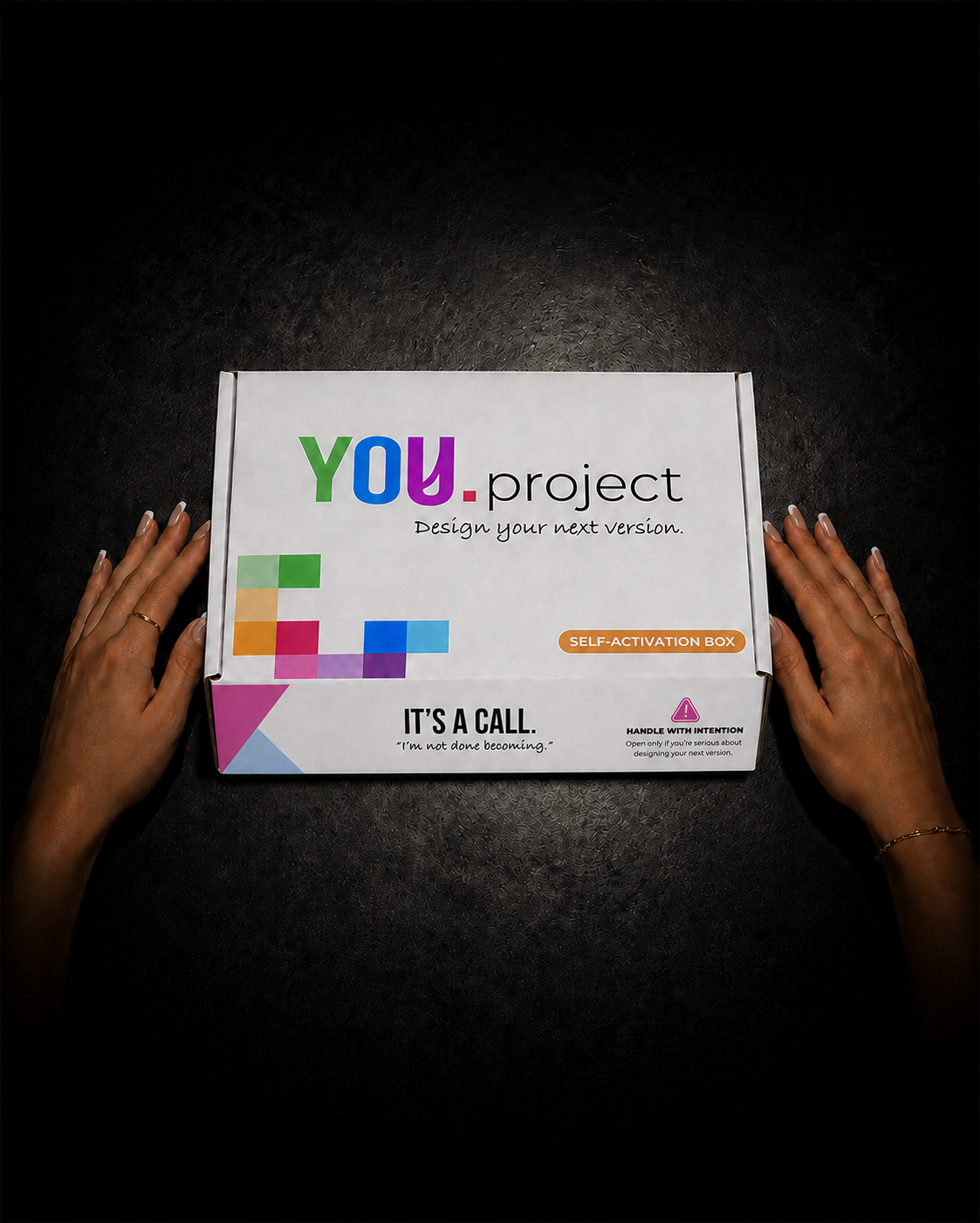 Hands preparing to open the YOU.project box on a dark concrete surface.