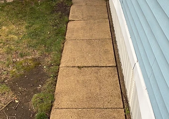 Concrete walkway running alongside light blue siding