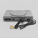 Grey PlayStation 1 console shown from the front with attached power and AV cables against a white background